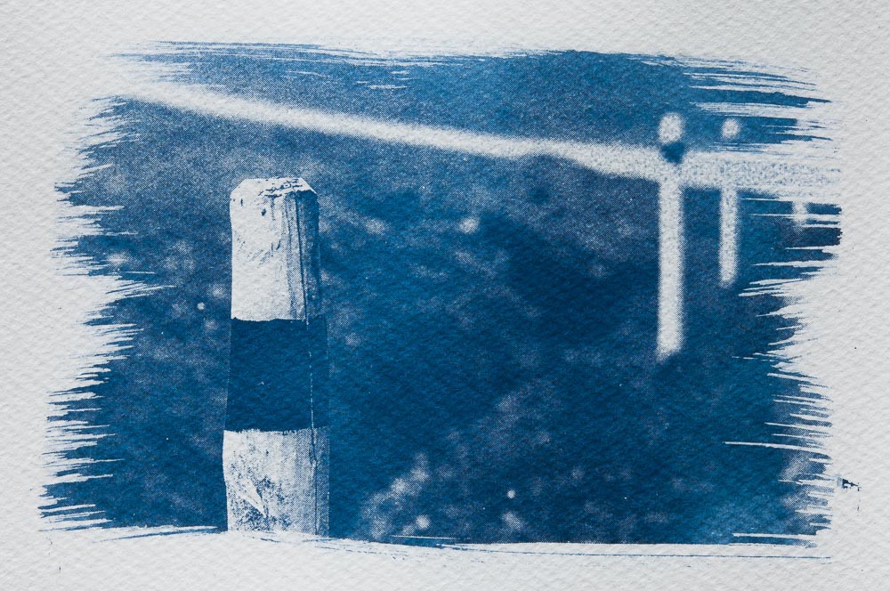 Cyanotype: three wooden reflector post with path in background