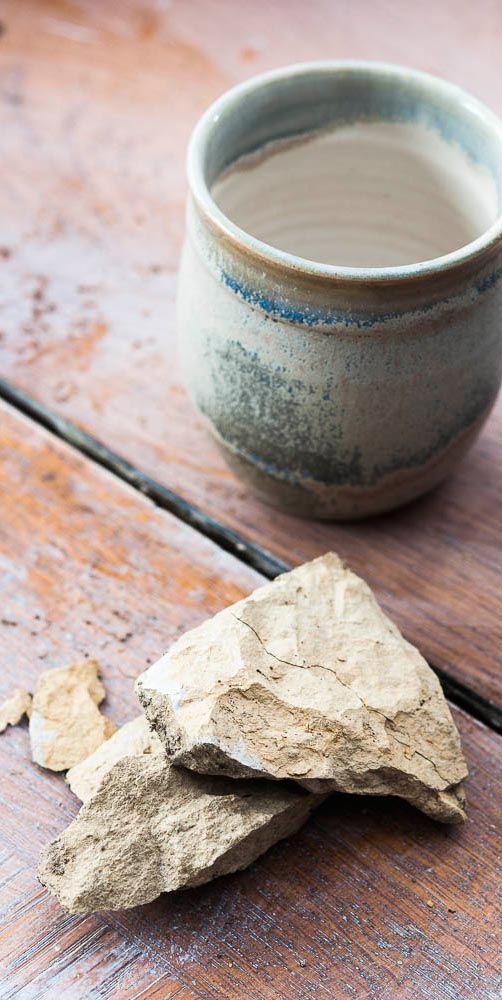 raw glaze ingredients in front of a clay pot