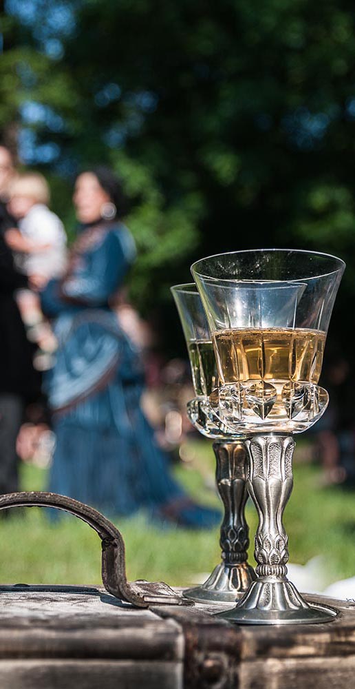 two goblets with beverage, family in background