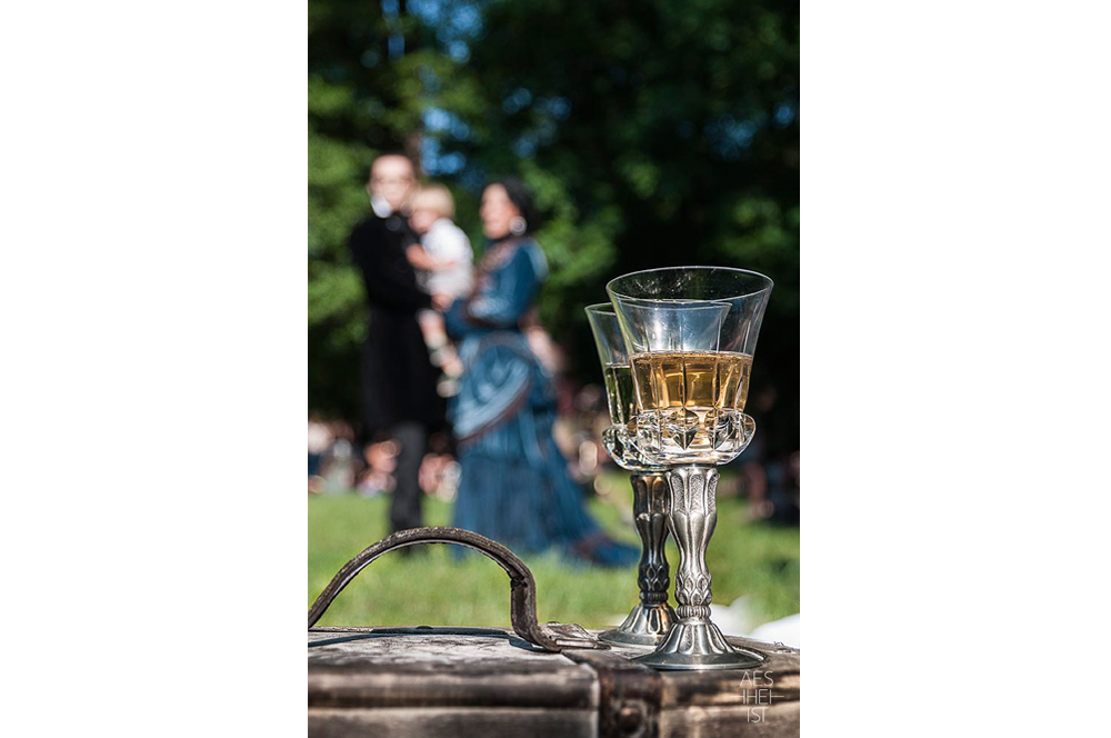 two goblets with beverage, family in background