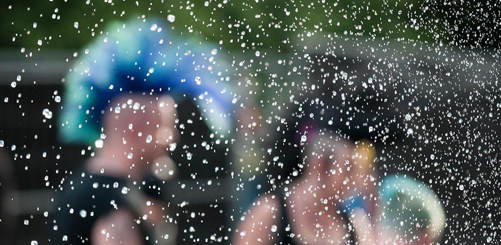 person with mohawk pictured through a fountain