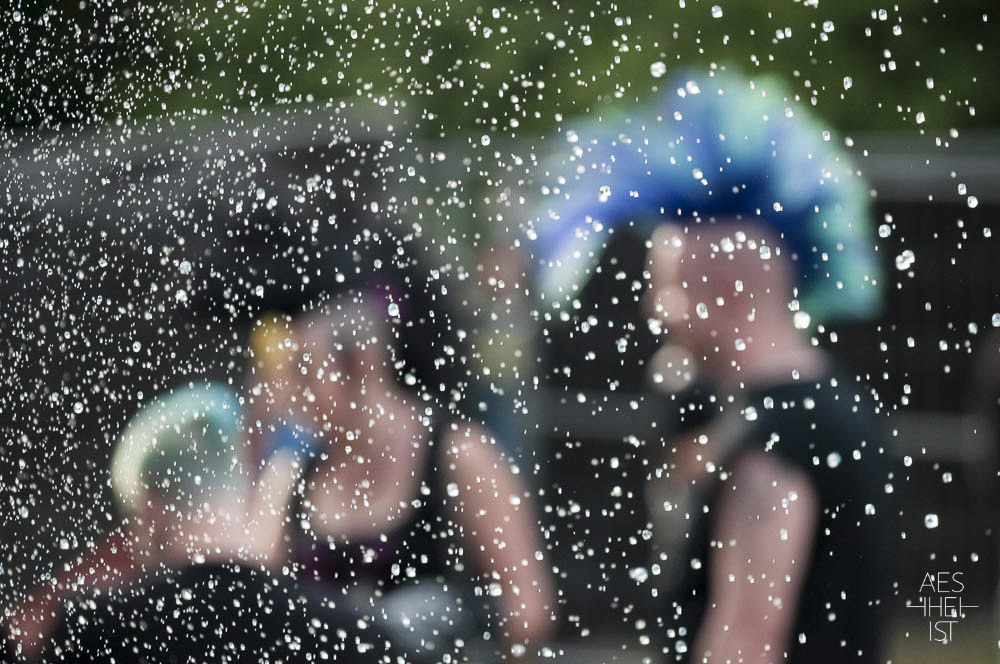 person with mohawk pictured through a fountain